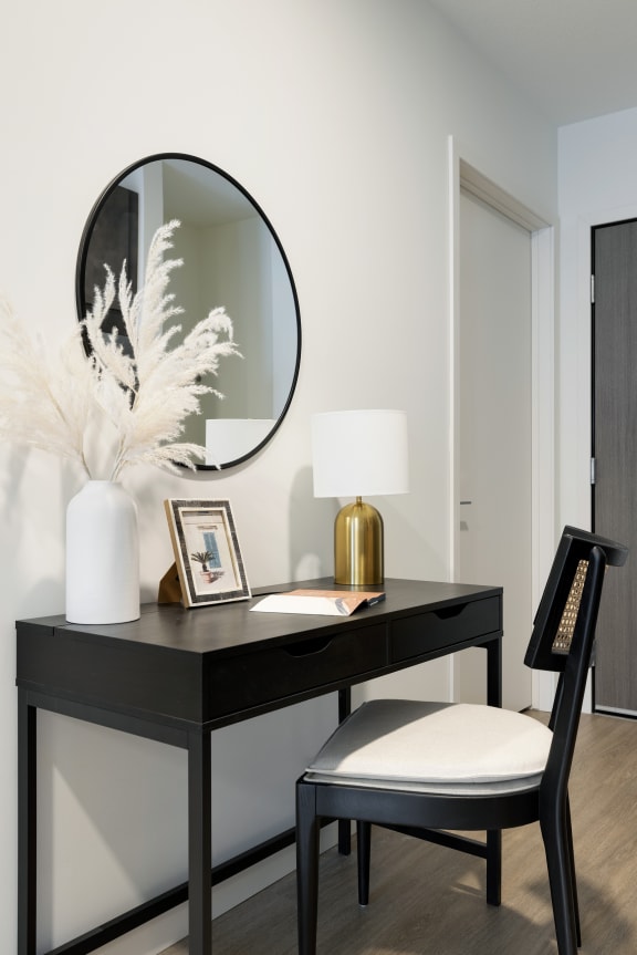 a black desk with a mirror and a white chair