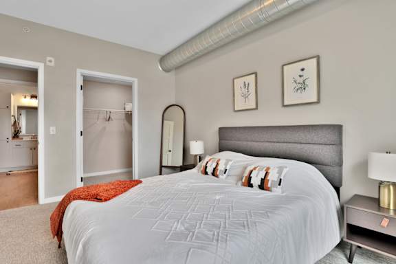 A bedroom with a large bed and a mirror on the wall.