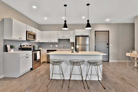 A modern kitchen with a center island and bar stools.