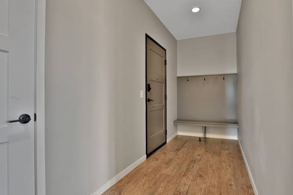 A hallway with a wooden floor and a white door.