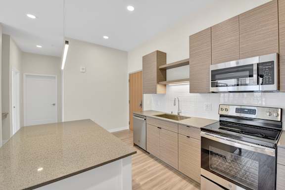 A modern kitchen with a granite countertop and stainless steel appliances.