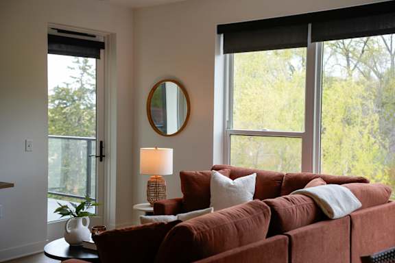 A living room with a red couch and a round mirror on the wall.