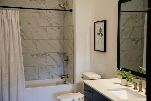 A bathroom with a marble tile shower and a white toilet.