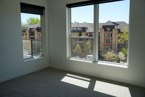 A room with two windows overlooking a residential area.