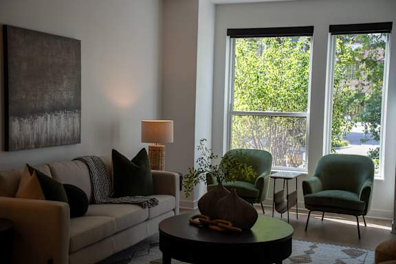 A living room with a couch, two chairs, a table, and a painting on the wall.