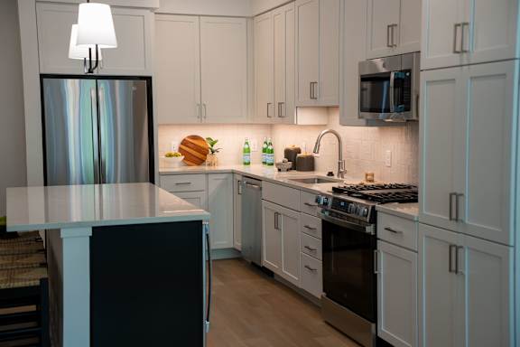 A kitchen with white cabinets and a black refrigerator.
