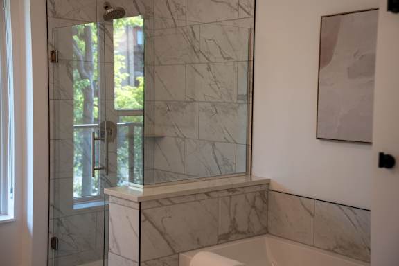 A bathroom with a marble shower and tub surround.