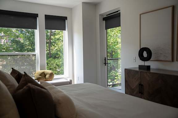 A bedroom with a large bed and a window with blinds.