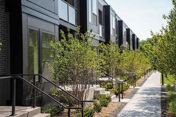 A long row of modern houses with trees in front.