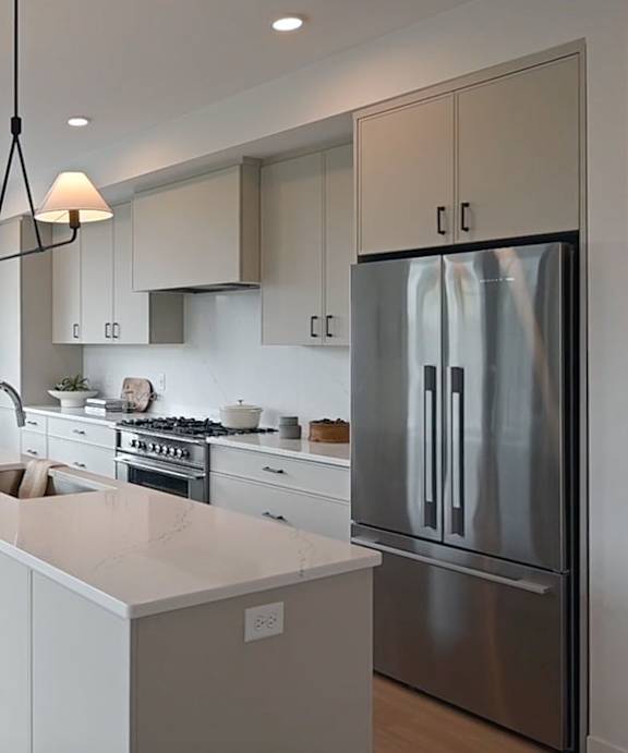 A modern kitchen with a stainless steel refrigerator and white countertops.