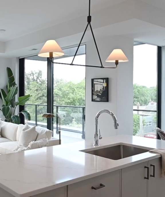 A modern kitchen with a white countertop and a large window.