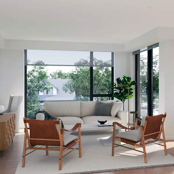 A modern living room with a white couch, two wooden chairs, and a large window.
