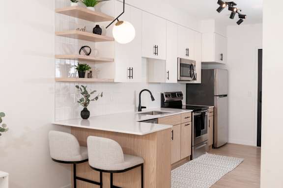 A modern kitchen with a white countertop and black appliances.
