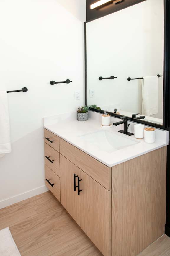 A bathroom with a sink, mirror, and towel rack.