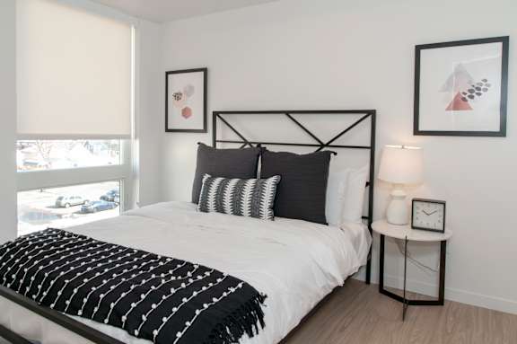 A bedroom with a white bed and black and white decor.