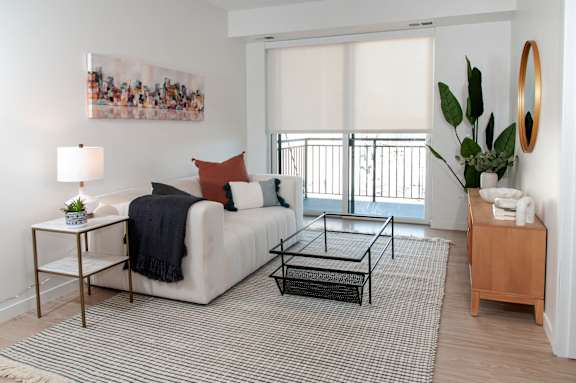 A living room with a white couch, a coffee table, and a painting on the wall.