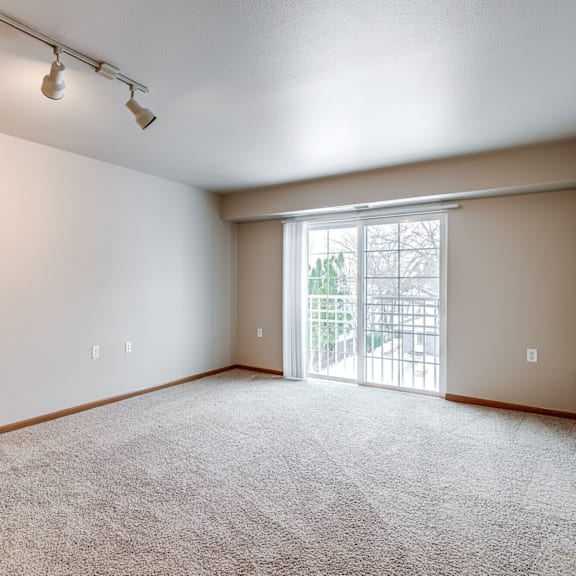 A room with a carpeted floor and a sliding glass door leading outside.