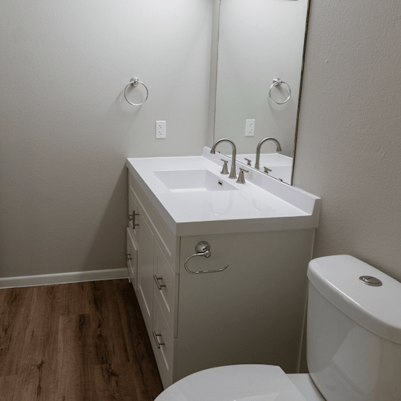 A white sink with a mirror above it and a toilet to the right.