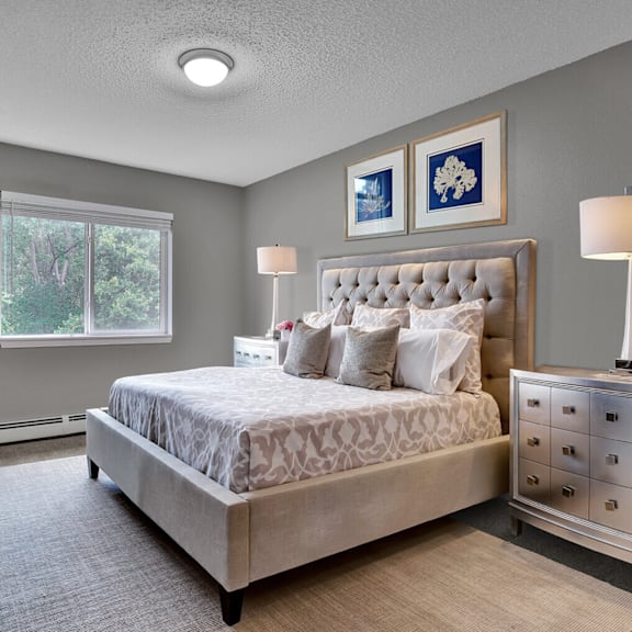 A bedroom with a large bed, two lamps, and two pictures on the wall.