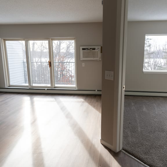 A room with a carpeted floor, a window, and a sliding glass door.