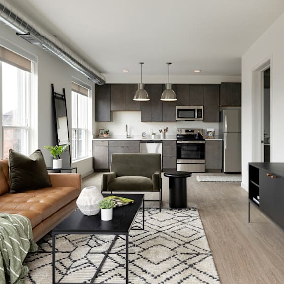A modern kitchen with a brown leather couch and a black coffee table.