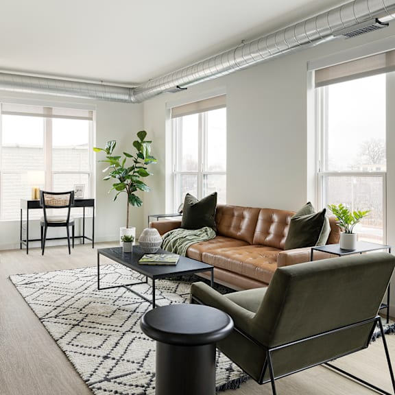 A living room with a brown leather couch, a black coffee table, and a green armchair.