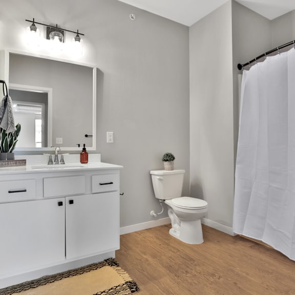 A white bathroom with a toilet, sink, and mirror.