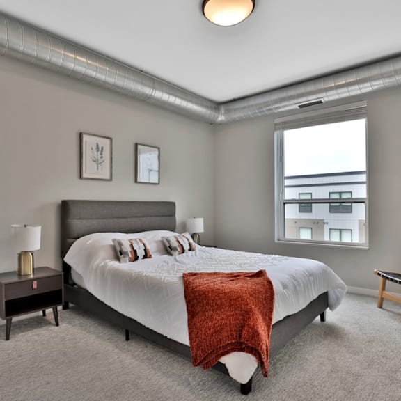 A bedroom with a large bed and a window overlooking a cityscape.