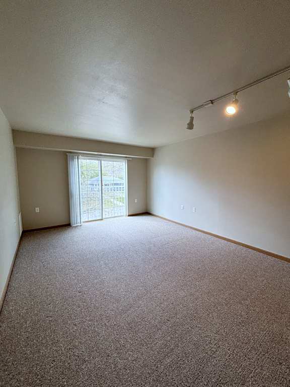 A room with carpeted floor and a window with blinds.