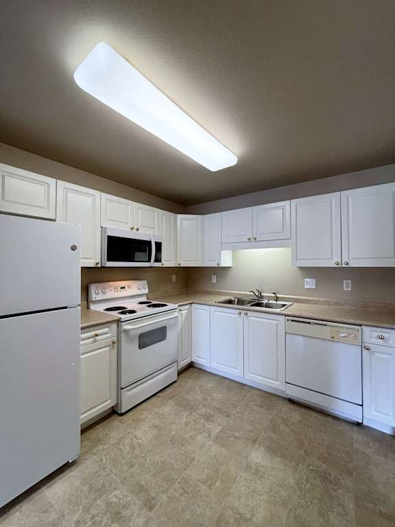 A kitchen with white appliances and cabinets.