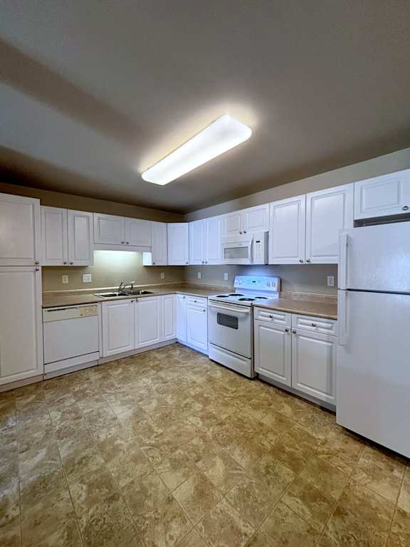 A kitchen with white cabinets and appliances.
