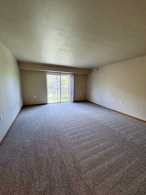 A room with a carpeted floor and a window with blinds.
