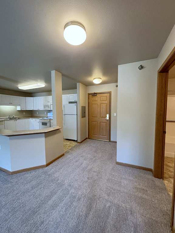 A kitchen with white cabinets and a white fridge.