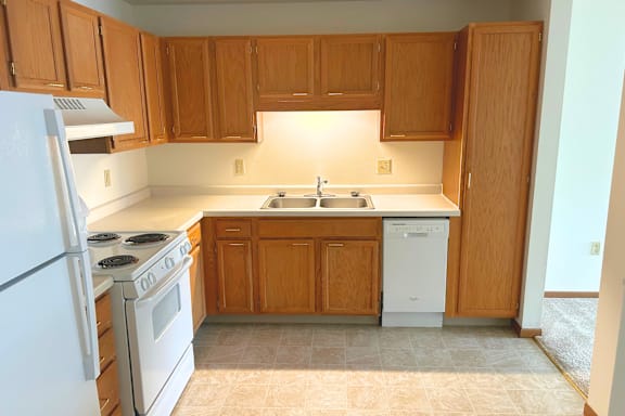 A kitchen with wooden cabinets and a white dishwasher.