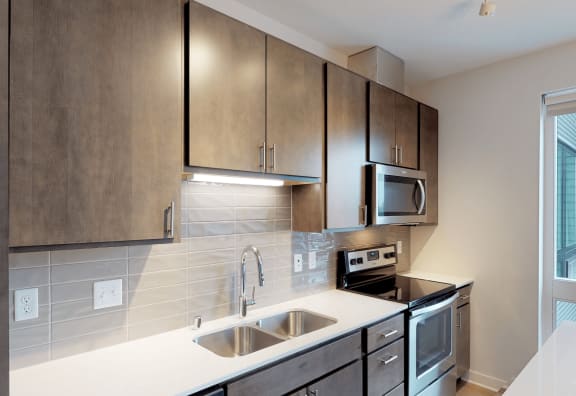 an empty kitchen with stainless steel appliances and wooden cabinets