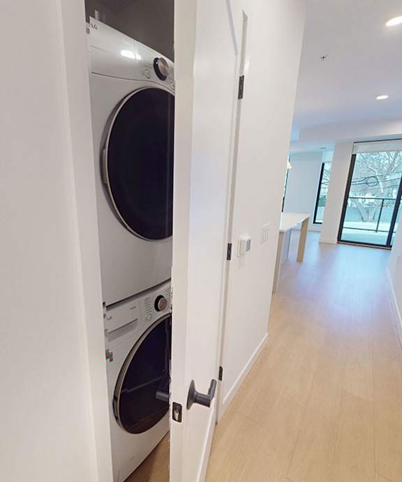 A white washing machine is in a narrow hallway.