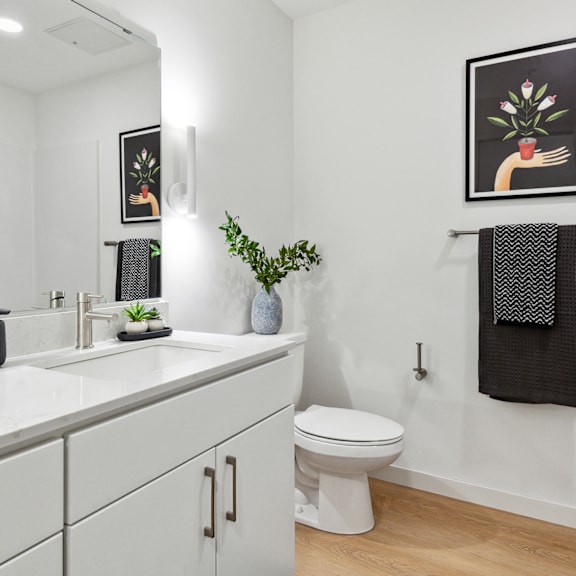 A white toilet sits in a bathroom next to a sink and a mirror.