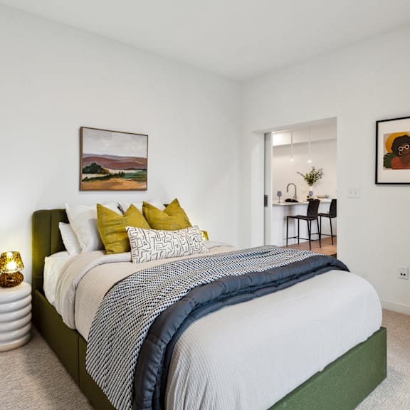 A bedroom with a large bed and a painting on the wall.
