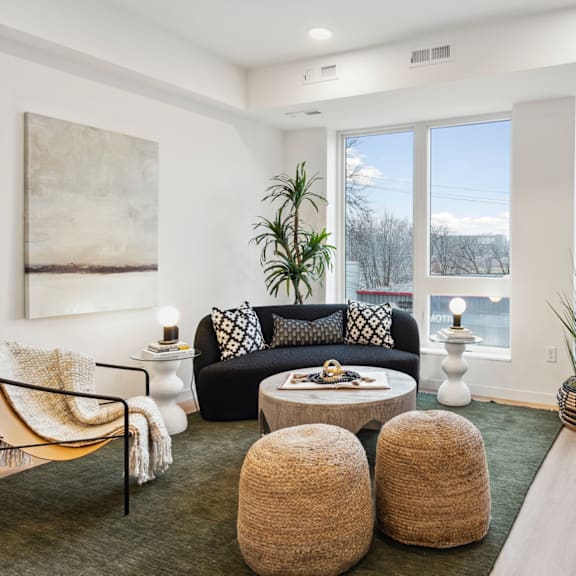 A living room with a black couch, a coffee table, and a large window.