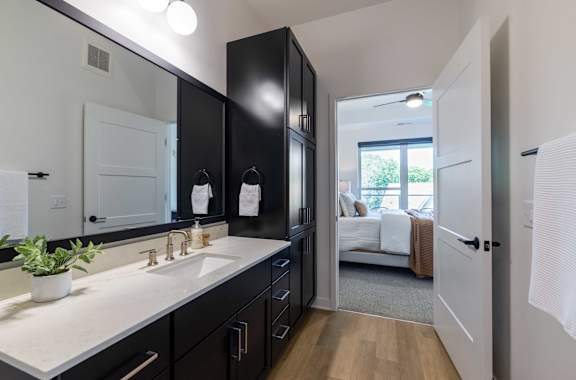 A bathroom with a white counter top and black cabinets.