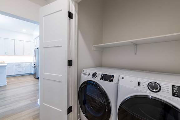 A white door is open to a laundry room with a washer and dryer.