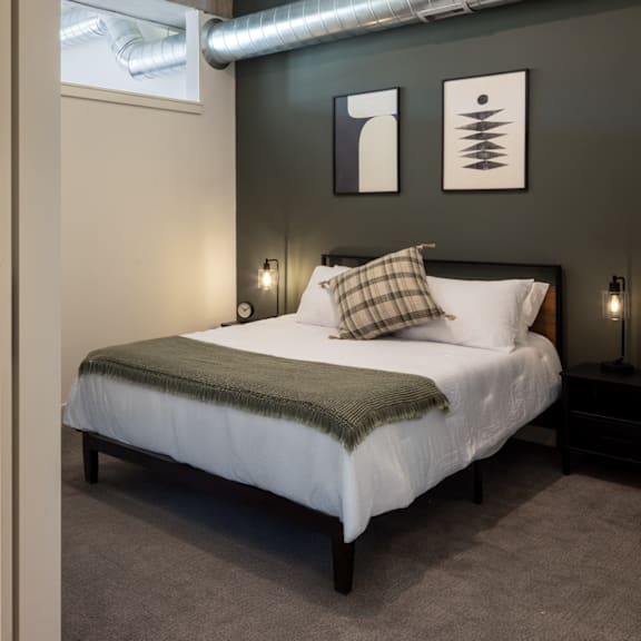 A bed with a white sheet and a plaid pillow is in the room.