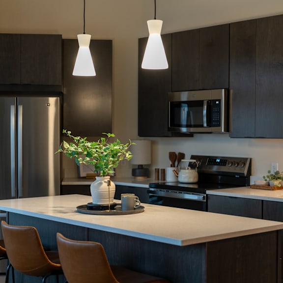 A kitchen with a white countertop and brown chairs.