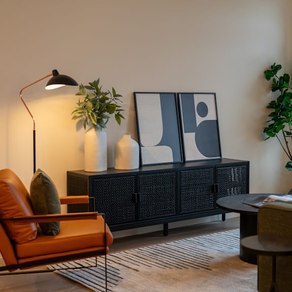 A living room with a black cabinet, a brown leather chair, and a black floor lamp.