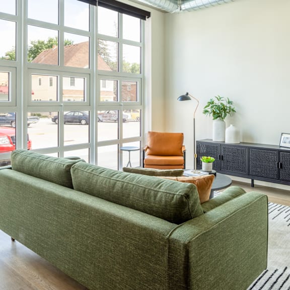 A living room with a green couch and a window overlooking a parking lot.