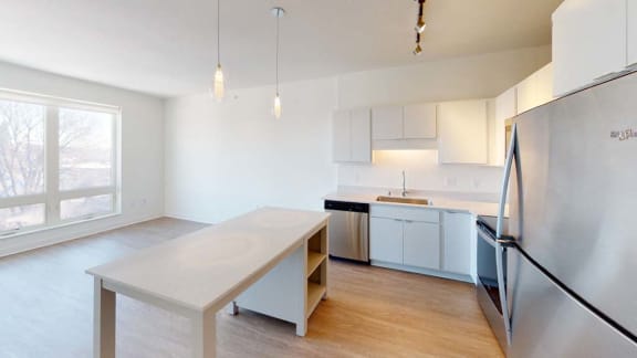 an empty kitchen with a table and a refrigerator