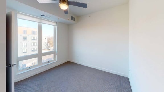 an empty room with a large window and a ceiling fan