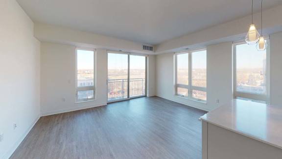 an empty living room with wood floors and large windows