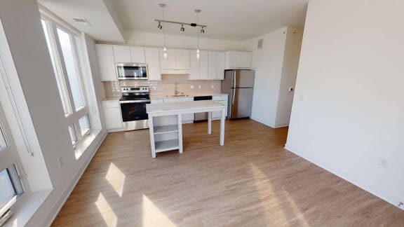 an empty kitchen with a white island and a refrigerator