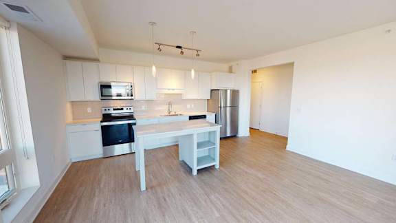 an empty kitchen with white cabinets and a counter top